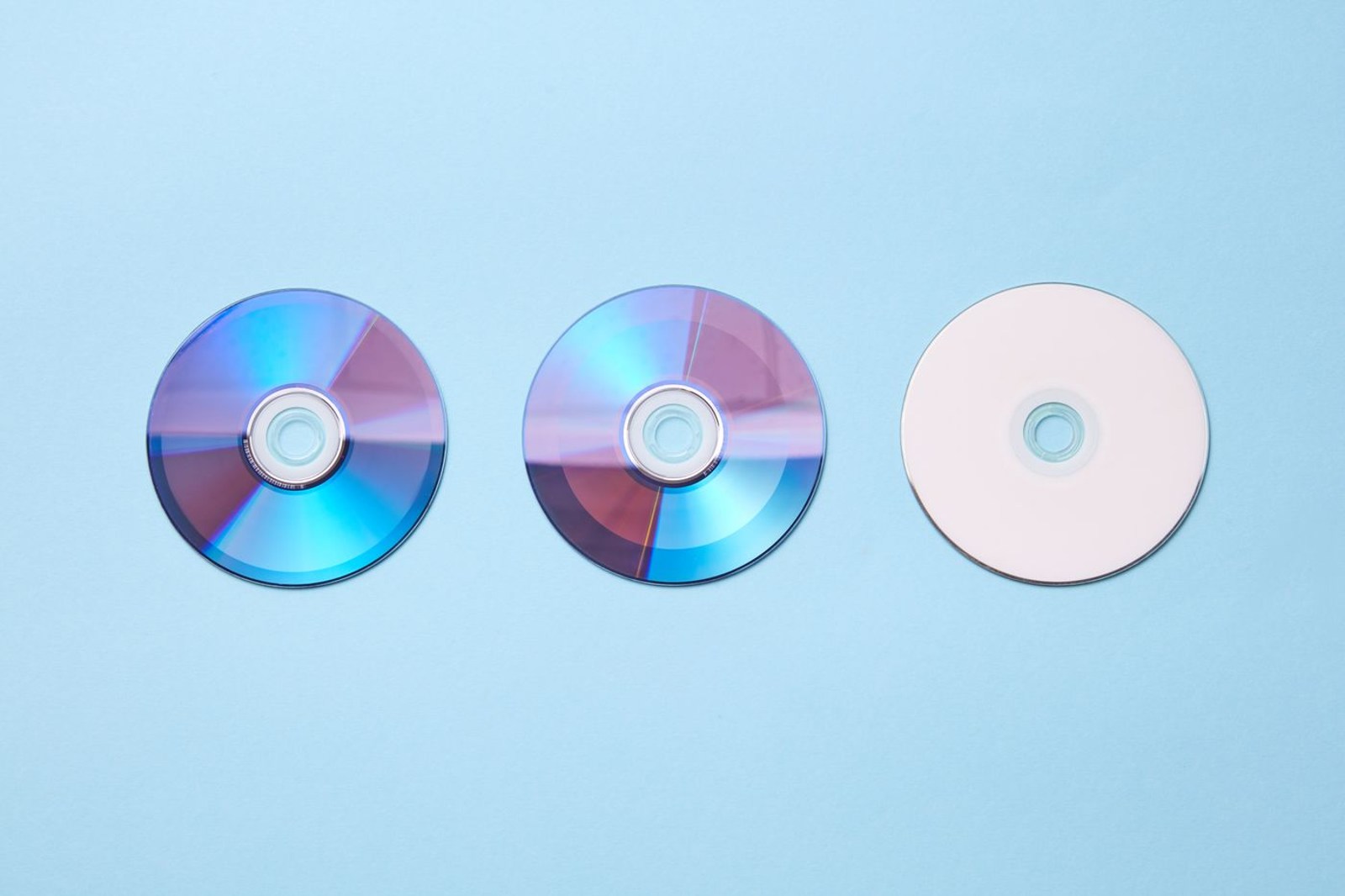 Three compact discs on a blue surface
